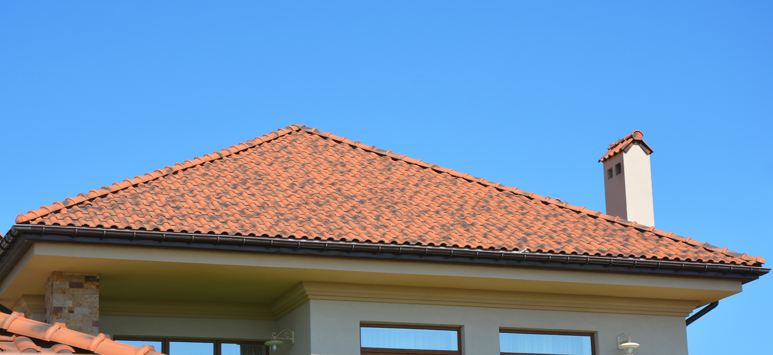 House with natural roof tiles. Home guttering, roof gutters, plastic guttering system.